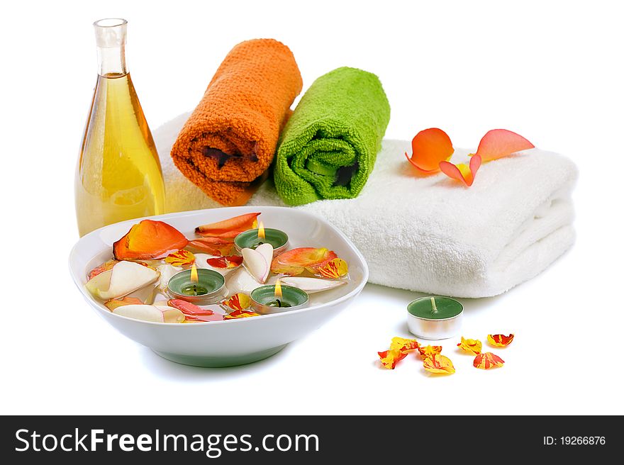 Bowl with rose petals, rose candle and towels on white background. Bowl with rose petals, rose candle and towels on white background