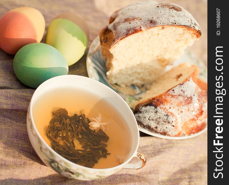 A china cup of green tea, a cake and three dyed eggs. A china cup of green tea, a cake and three dyed eggs
