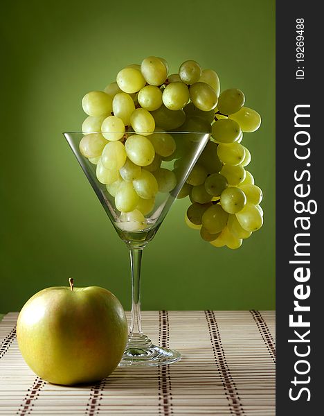 Grapes in a martini glass and an apple food still life. Grapes in a martini glass and an apple food still life