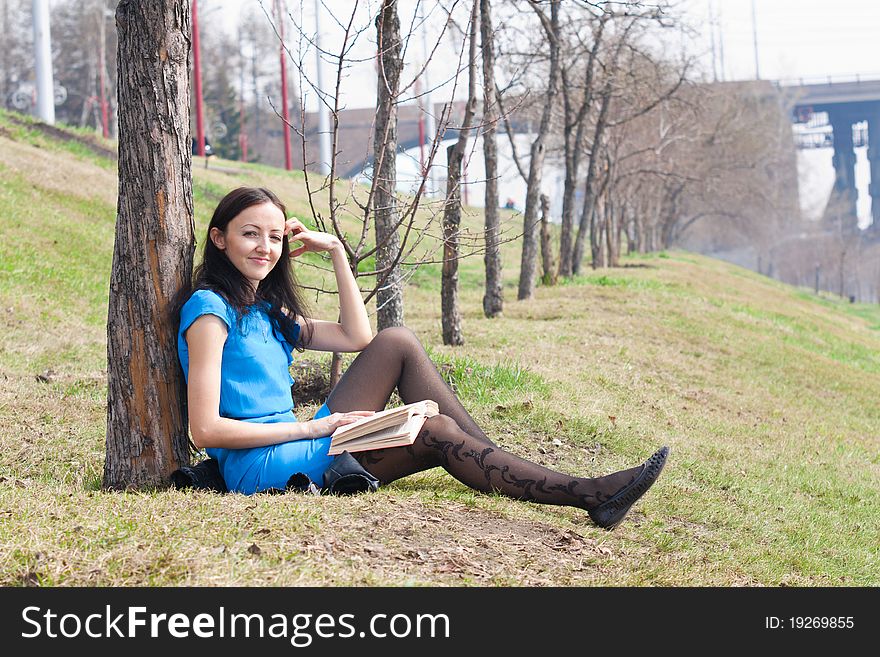 Girl reading book in spring park in the open air