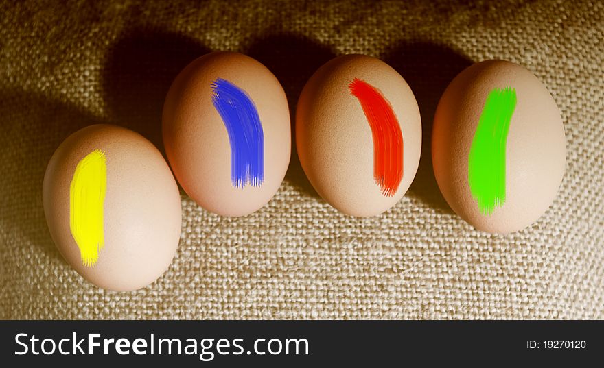 Four brown eggs on the sackcloth with colors. Four brown eggs on the sackcloth with colors.