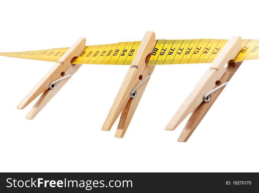 Three clothespins on the yellow measuring tape isolated a white surface. Three clothespins on the yellow measuring tape isolated a white surface.