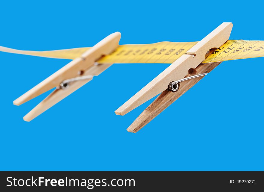 Clothespins and measuring tape isolated on a blue surface. Clothespins and measuring tape isolated on a blue surface.