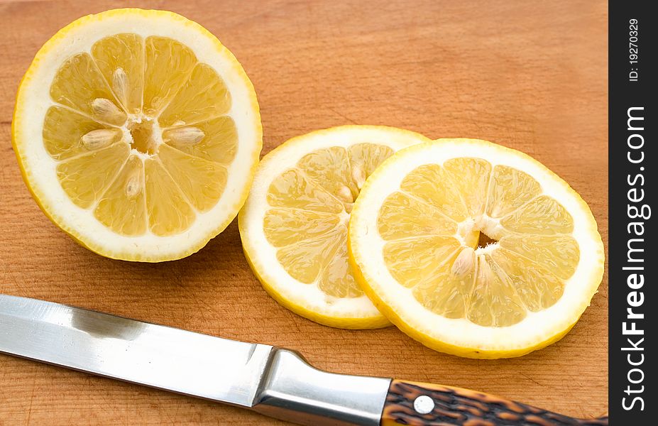 Sliced lemon rings on the board and knife.