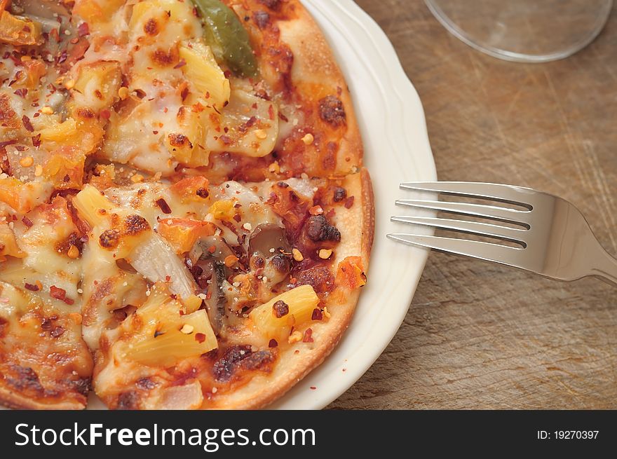 Vegetable and fruit pizza on plate with wooden background.