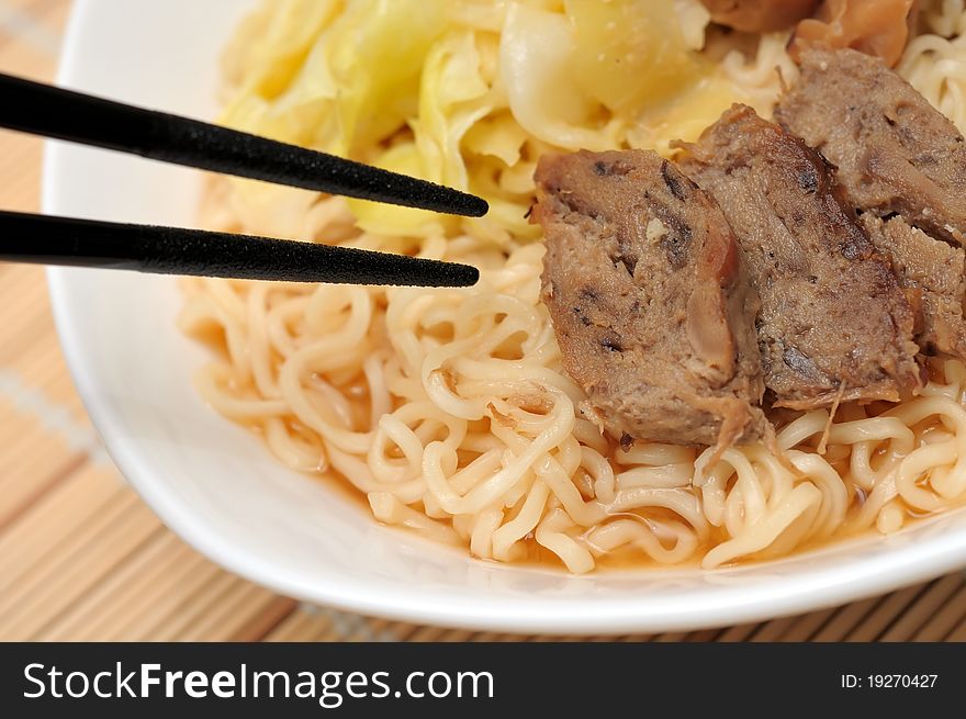 Japanese style chopsticks eating tasty yellow noodles with meat pieces. Japanese style chopsticks eating tasty yellow noodles with meat pieces.