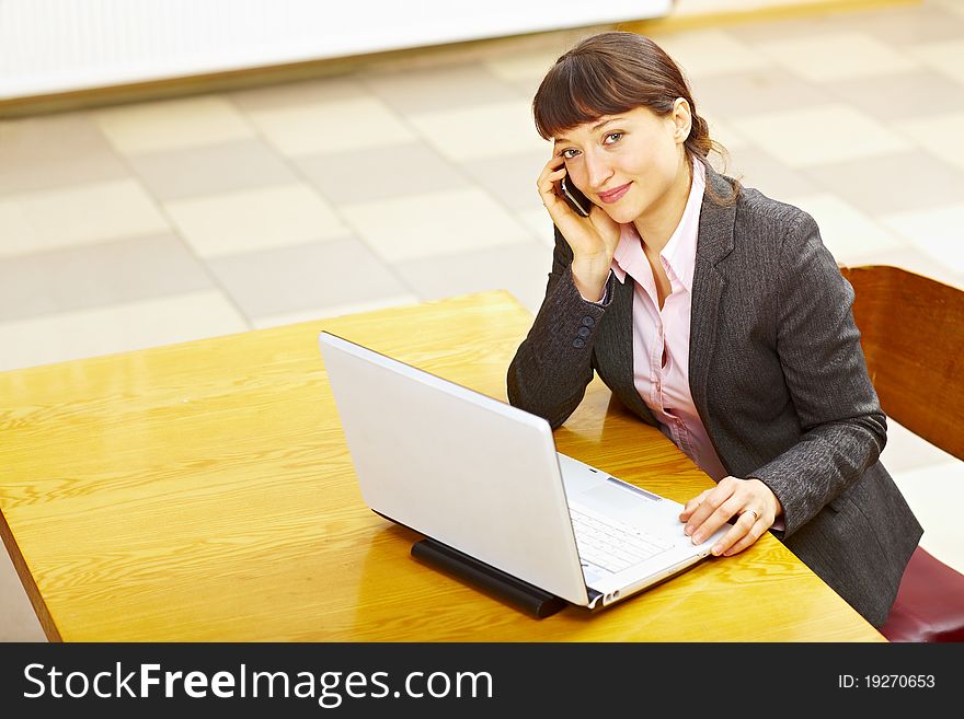 Business woman sitting with laptop and talking on the phone. Business woman sitting with laptop and talking on the phone