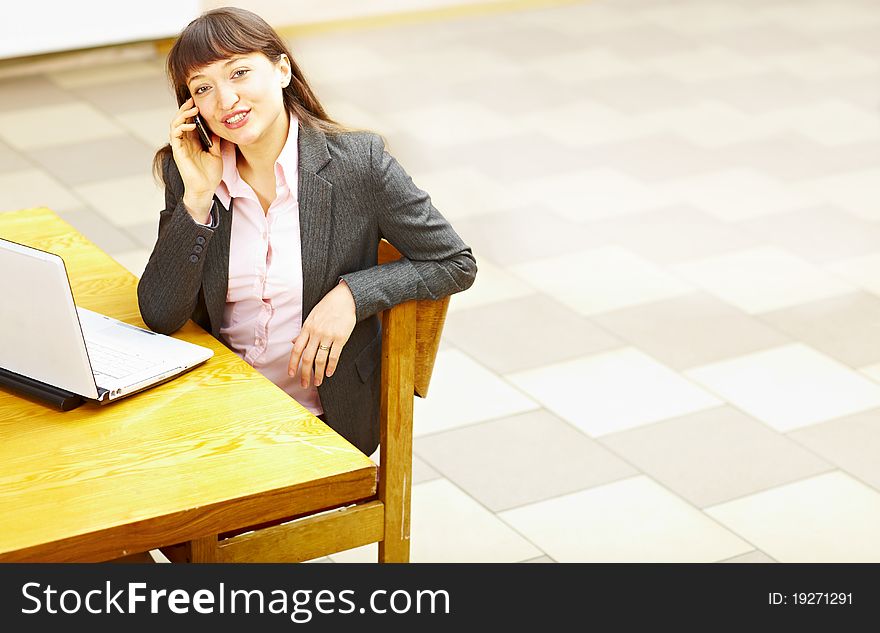 Business woman sitting with laptop and talking on the phone. Business woman sitting with laptop and talking on the phone