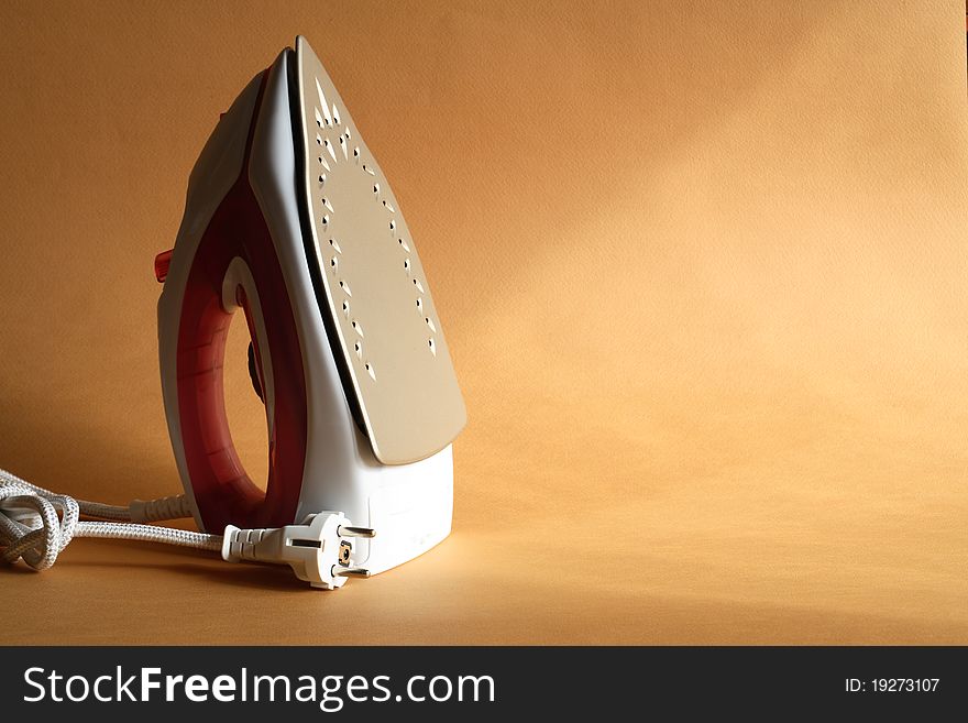 Modern electric iron standing on nice gold background with sun lighting