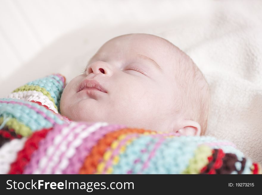 Newborn baby wrapped up asleep in a stripet shawl. Newborn baby wrapped up asleep in a stripet shawl