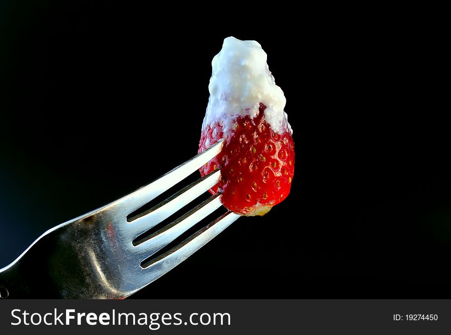 Against a black background photographed strawberries with cream pin at the plug