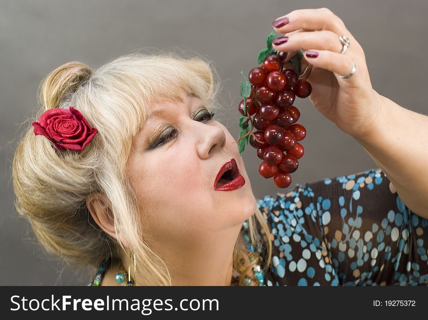 Portrait of a beautiful middle-aged women with red grape