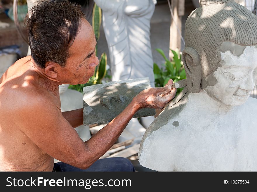 Restore buddhist figure, old Asian man with his craft