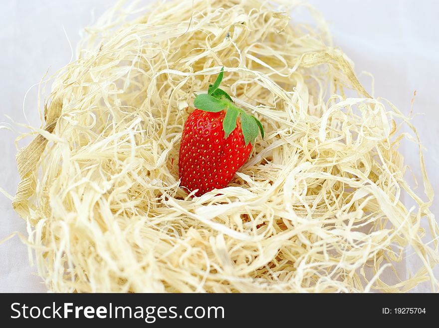 A Strawberry In The Hay On A White Background