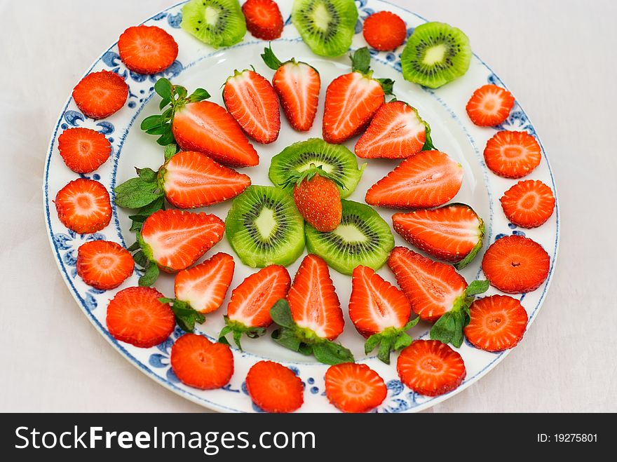 Fresh strawberries and kiwi fruit sliced on a plate on white background