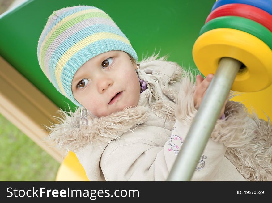 The Girl In A Coat On A Playground
