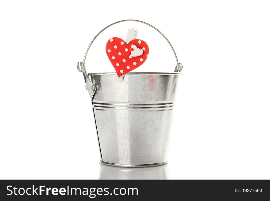 Metal bucket isolated on a white background. On the bucket wooden clothespin with a red heart. Metal bucket isolated on a white background. On the bucket wooden clothespin with a red heart