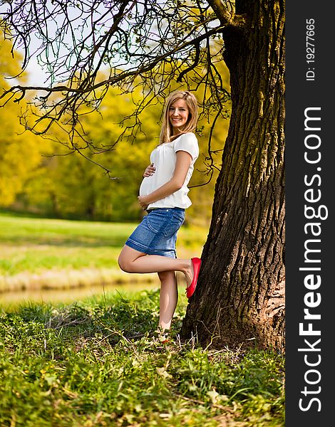 Pregnant woman outdoor in park at spring time