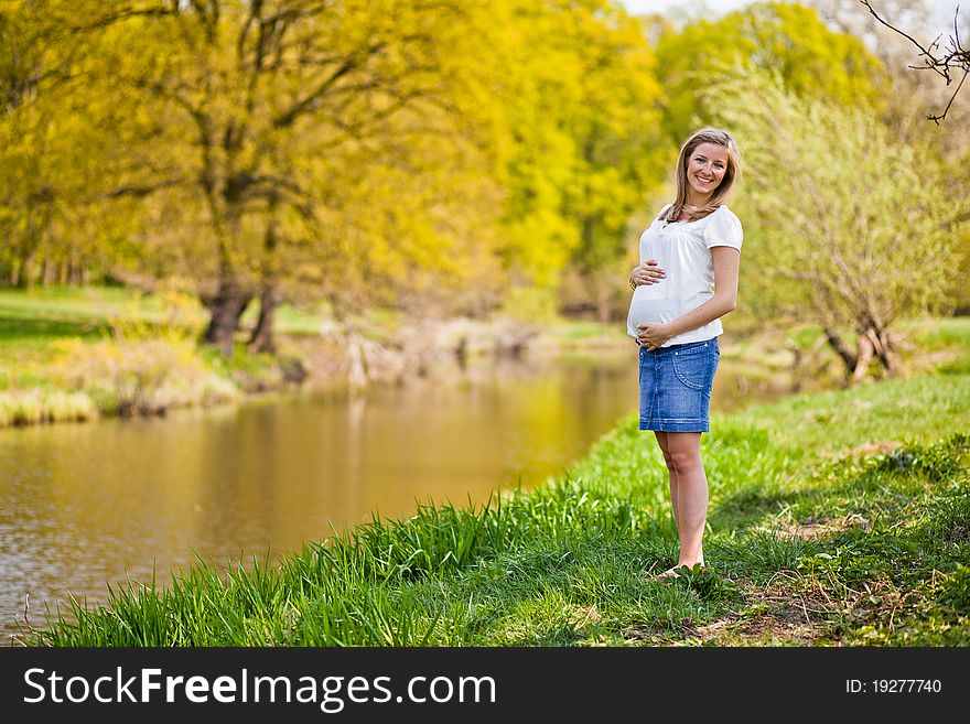 Pregnant woman outdoor in park at spring time