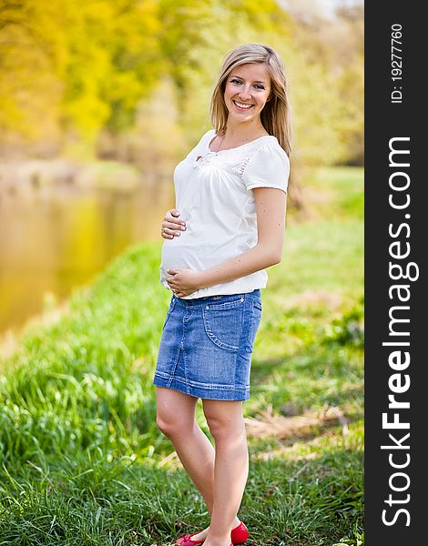 Pregnant woman outdoor in park at spring time