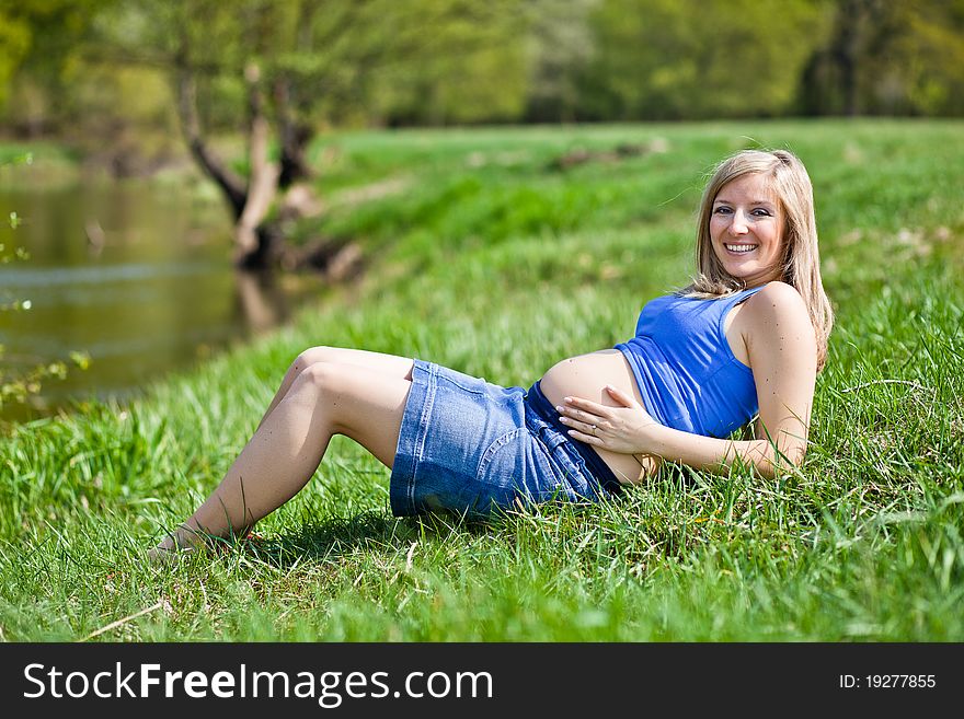 Pregnant woman outdoor in park at spring time