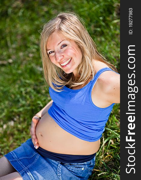 Pregnant woman outdoor in park at spring time