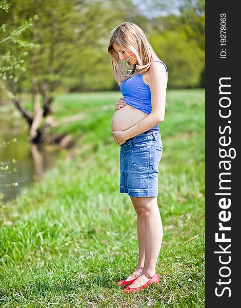 Pregnant woman outdoor in park at spring time