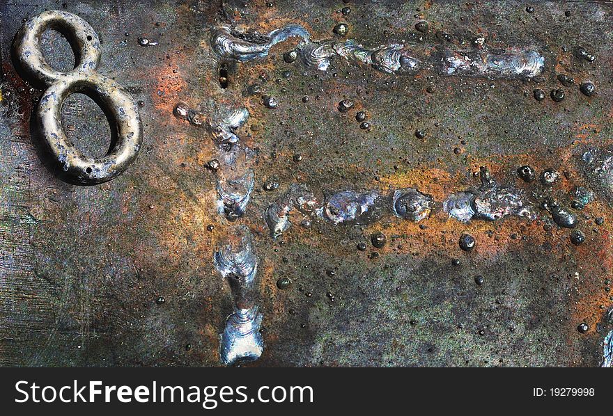 Corrosion and rust, as well as textures only found with weathered, metallic surfaces. A scarred and oxidized number 8 and what appears as the letter F, welded onto the surface, are the dominant elements. Corrosion and rust, as well as textures only found with weathered, metallic surfaces. A scarred and oxidized number 8 and what appears as the letter F, welded onto the surface, are the dominant elements.