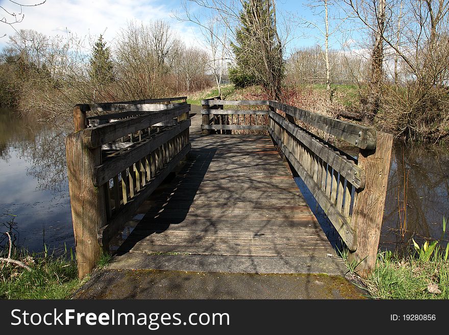 A wooden bridge crossing over a pond in a park. A wooden bridge crossing over a pond in a park.