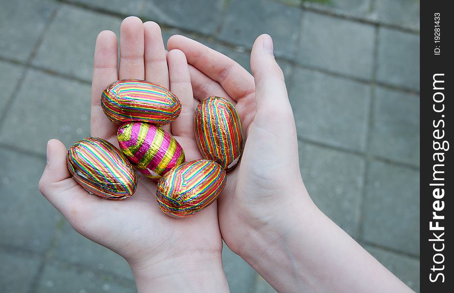 Hands of a teenager holding a hand full of Easter suprise eggs. Showing of the Easter eggs he found during the Easter hunt. Hands of a teenager holding a hand full of Easter suprise eggs. Showing of the Easter eggs he found during the Easter hunt.