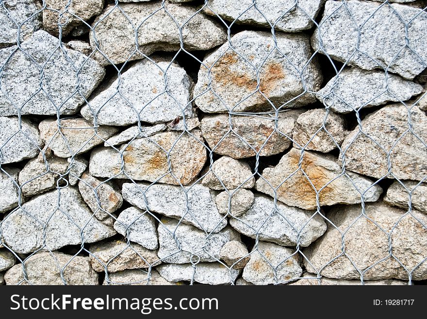 Stone wall made of stones laid in a metal grid