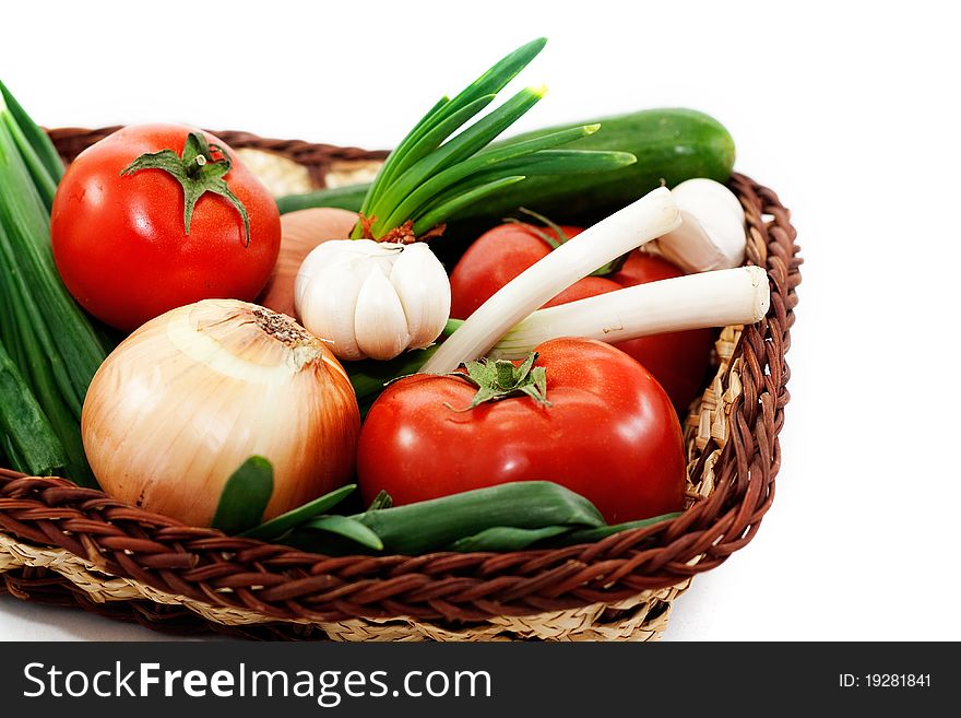 Tomatoes, cucumbers, green onions, garlic in a wicker basket isolated on white background. Tomatoes, cucumbers, green onions, garlic in a wicker basket isolated on white background