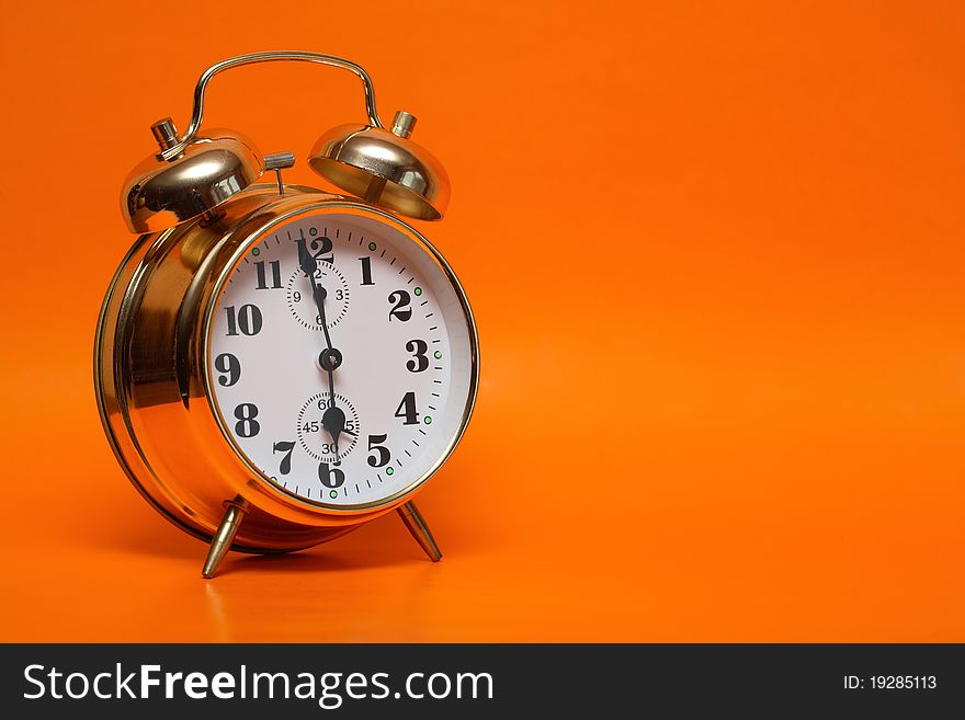 Gold alarm clock standing on nice ginger background with copy space