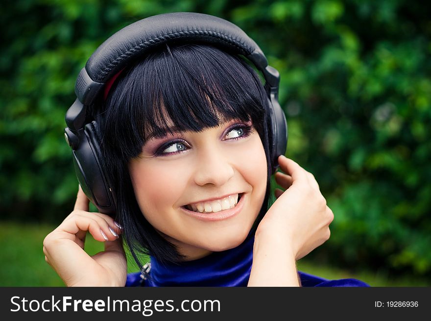 Happy young woman listening to music with headphones; green background. Happy young woman listening to music with headphones; green background.