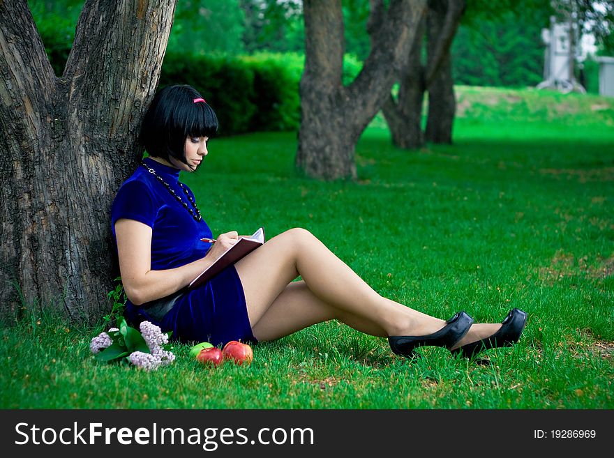 Portrait of attractive young woman with black hair; green nature background