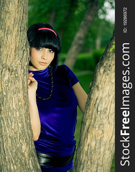 Portrait of attractive young woman with black hair; green nature background