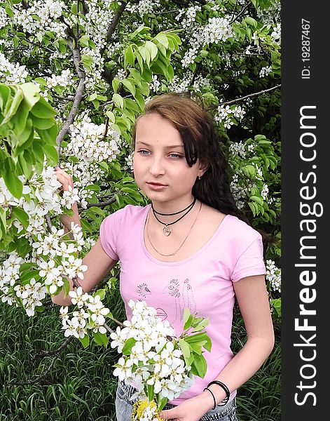 Girl among the blossoming apple trees in spring