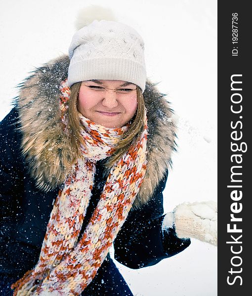 Attractive young woman in wintry coat with large fur head, snowy in background.