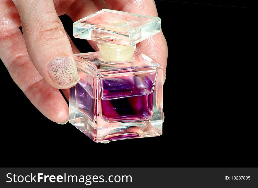 Perfume bottle in a hand on a black background. Perfume bottle in a hand on a black background