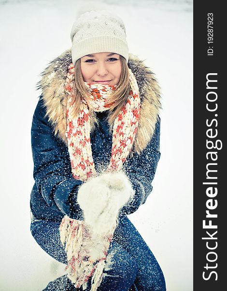 Attractive young woman in wintry coat with large fur head, snowy in background.