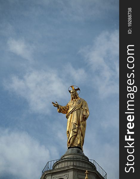 A golden statue of Jesus standing high over the streets of Rome. A golden statue of Jesus standing high over the streets of Rome.