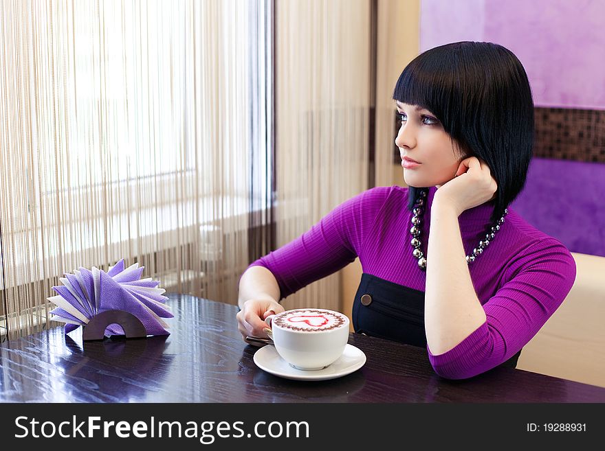 Young woman in cafe with large cap of coffee