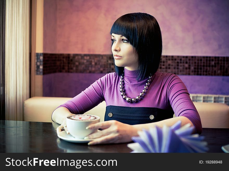 Young woman in cafe with large cap of coffee