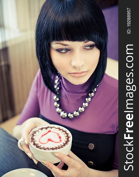 Young woman in cafe with large cap of coffee