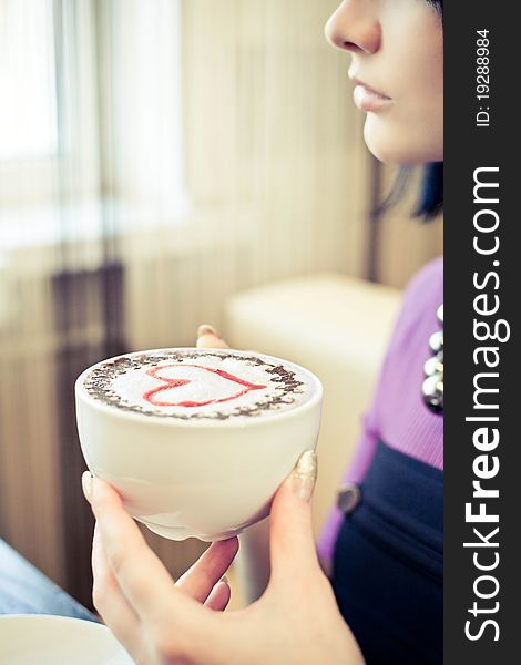 Young woman in cafe with large cap of coffee