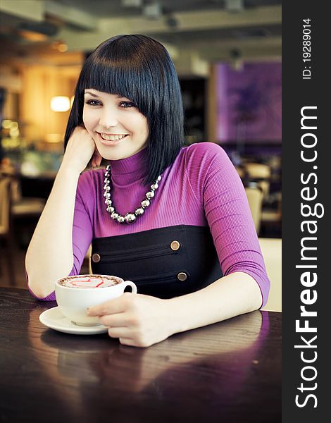 Young woman in cafe with large cap of coffee