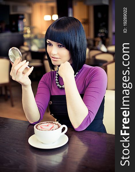 Young woman in cafe with large cap of coffee