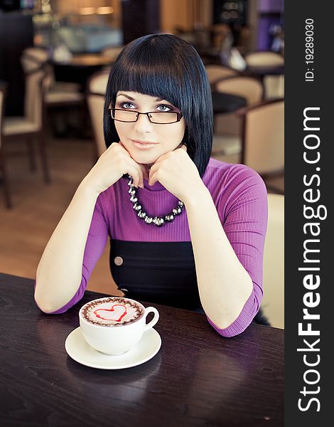 Young woman in cafe with large cap of coffee