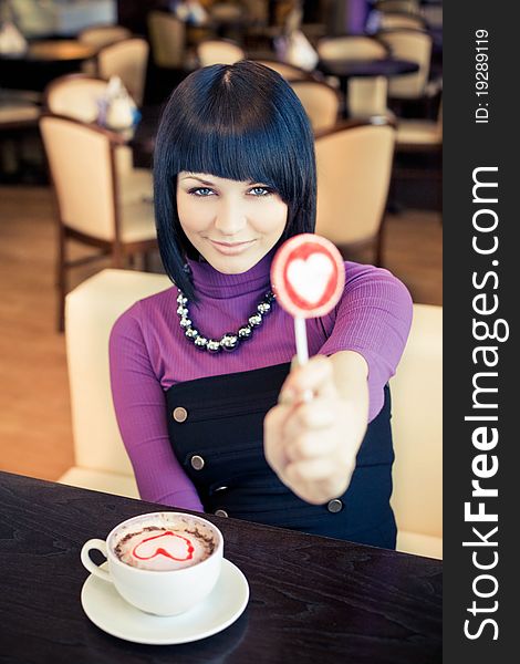 Young woman in cafe with large cap of coffee