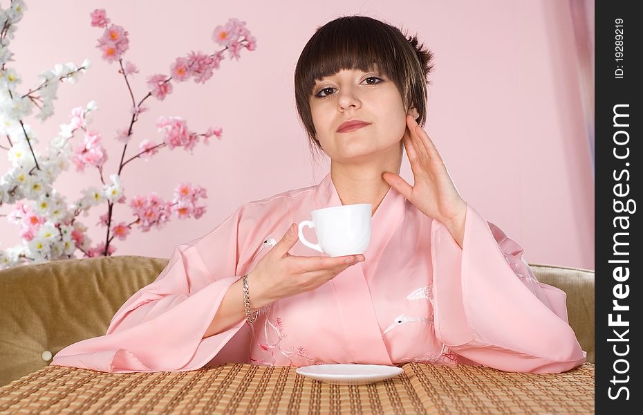 Beautiful girl sitting on a pink background